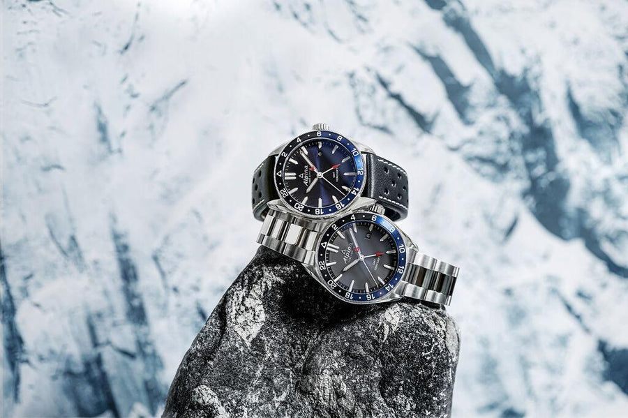 Two Alpina Alpiner watches placed on a snow-covered rock